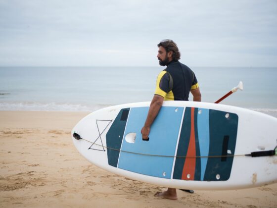 Homme en combinaison de paddle sur la plage