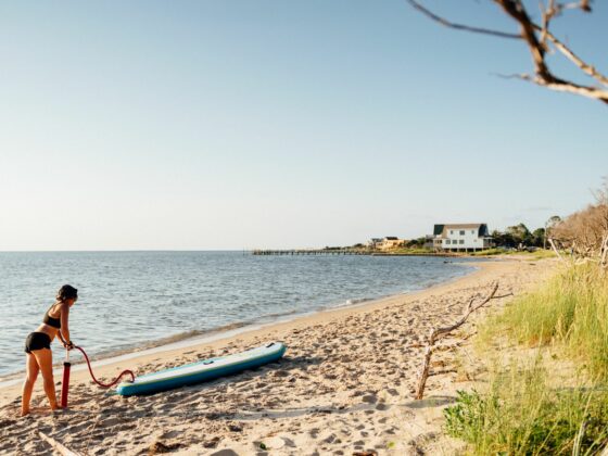 Femme qui gonfle son paddle sur la plage