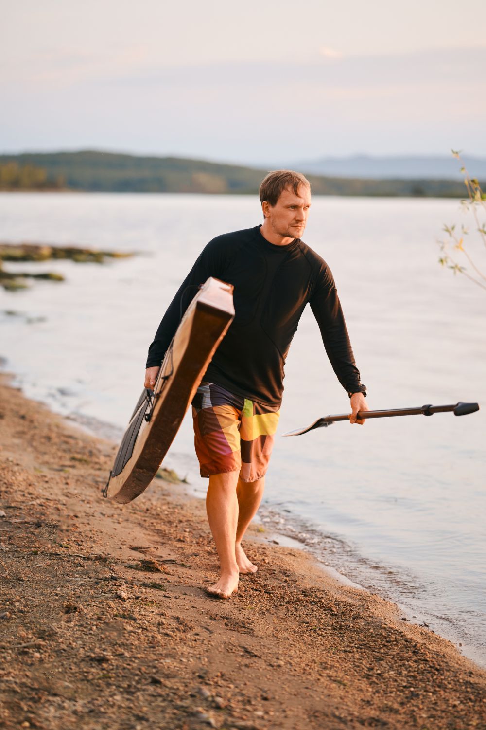 Homme qui porte une planche de paddle